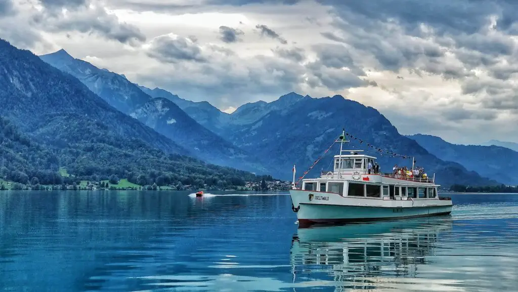 1 day in Interlaken, boat on the lake, blue skies, and clouds with mountains in the background