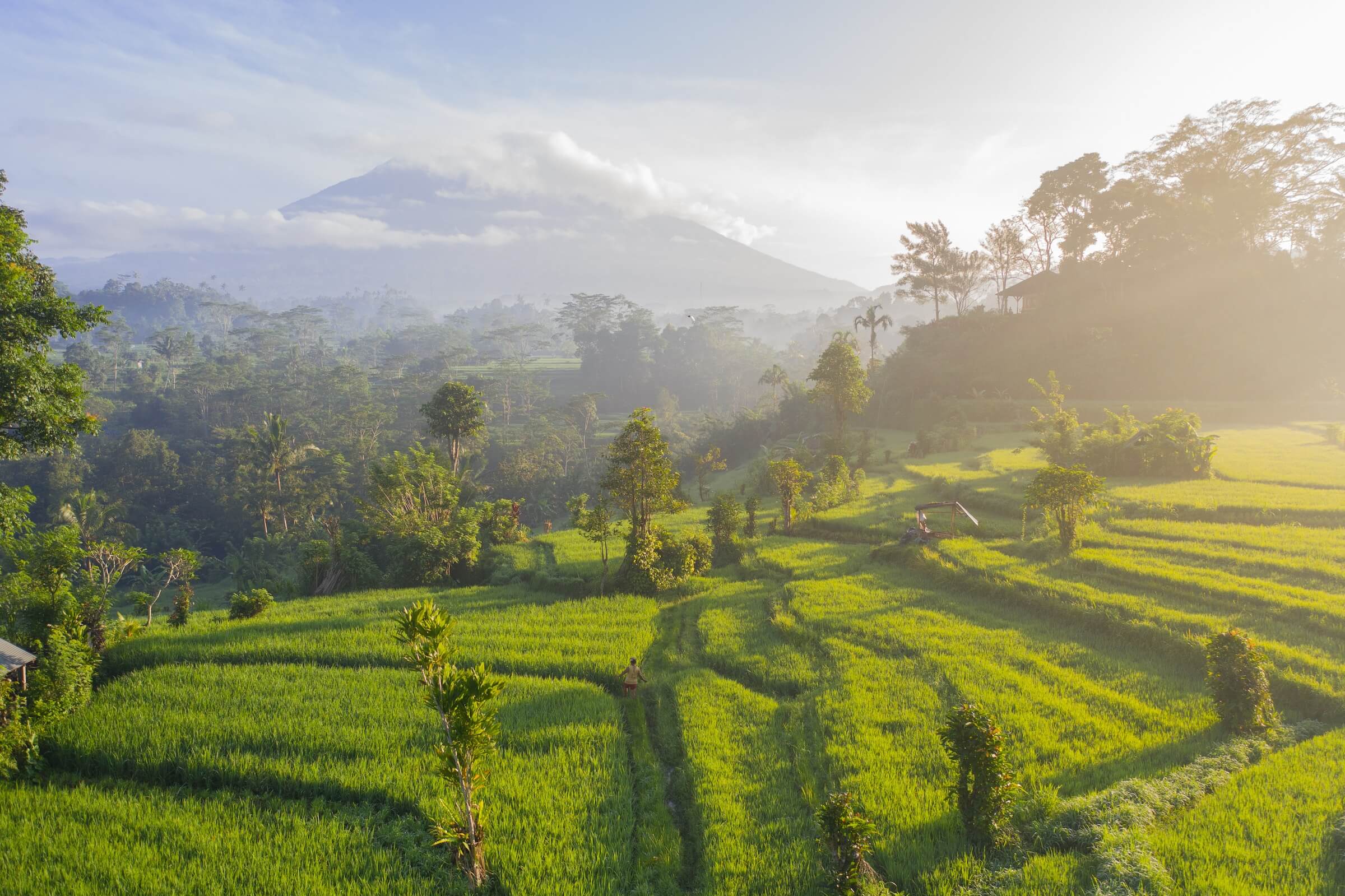3 days in Bali itinerary. This is an image of Mount Agung with clouds at its top and surrounded by lush green terraced rice fields.