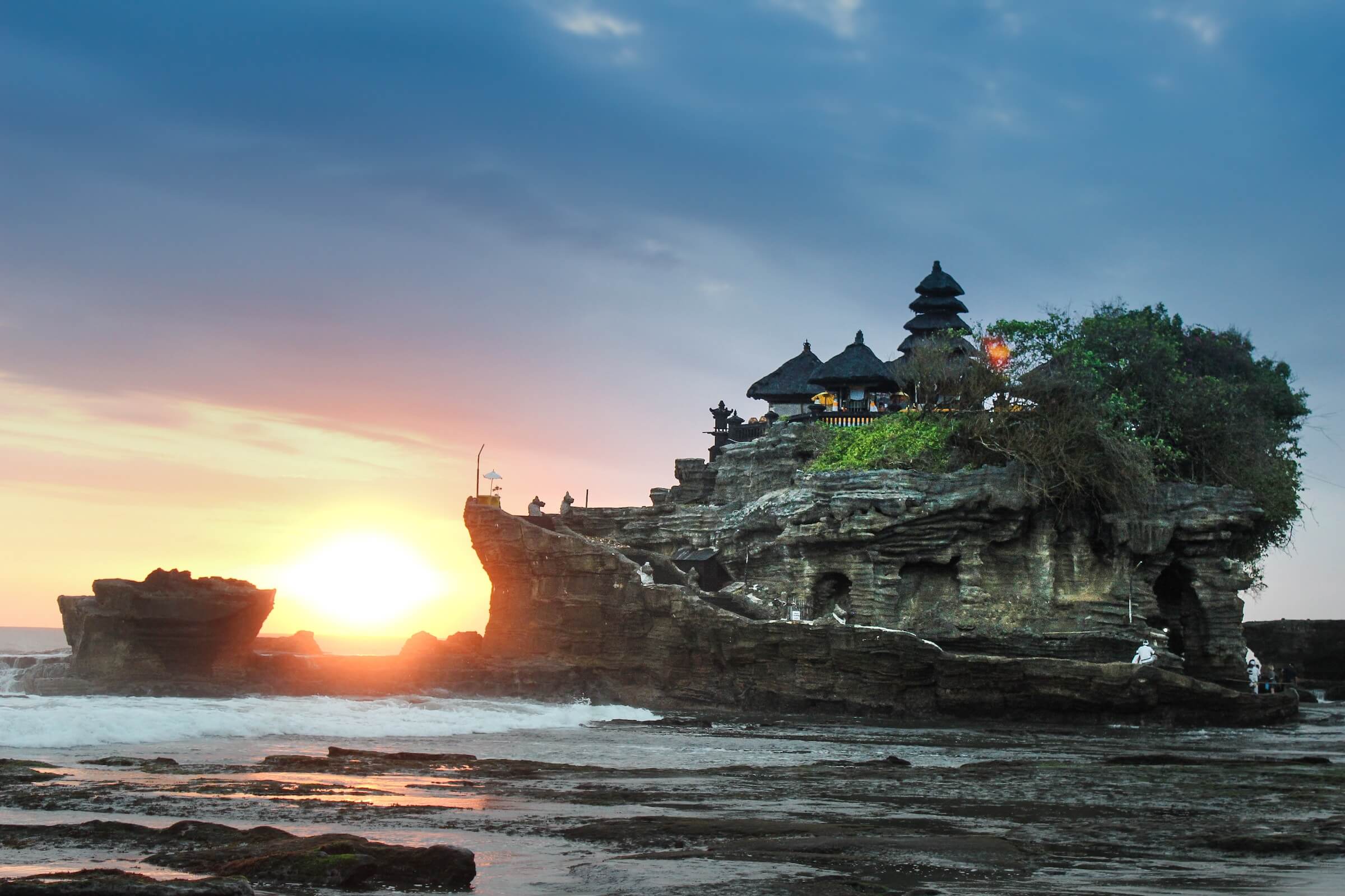 7 days in Bali itinerary, An image of Tanah Lot during sunset with the sun just above the horizon and between the two rocky outcrops of Tanah Lot Temple