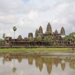 This is the featured image for 13 reasons to visit Angkor Wat. This is an image of Angkor Wat at one of the reflection ponds at noon.